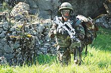 A French soldier stands guard amongst some ruins in the Joint Multinational Readiness Center training area in Hohenfels, Germany, May 14, 2008. The NATO Operational Mentorship and Liaison Team is preparing the soldiers for unit readiness prior to a deployment. French Army FAMAS + Aimpoint.jpg