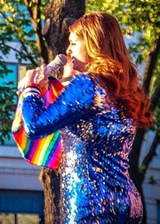 Meghan Trainor performing on stage with a rainbow flag