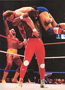 Mr T. hoists Roddy Piper up onto his shoulders as Hulk Hogan cheers in the background during the main event Mr T at WrestleMania, 1985.jpg