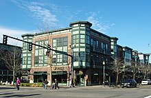 Picture of a three-story brick building fronting a large intersection in the Orenco Station neighborhood. On the ground floor is what appears to be a restaurant.