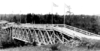 A black and white photograph of a wooden bridge.