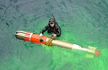 Retrieval of a Mark 46 exercise torpedo. Note the dye, used to locate the weapon, and the wire rope attached to the nose cage to bring the weapon aboard. Search and rescue swimmer Quartermaster 2nd Class Justin Peel, from Polson, Mont., secures an MK-46 exercise torpedo to be hoisted aboard the guided missile cruiser USS Vincennes (CG 49).jpg