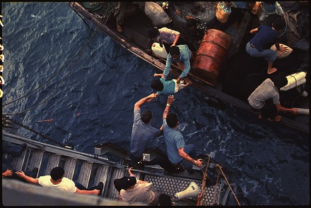 Crewmen of the USS Durham (LKA-114) take Vietnamese refugees from a small craft in 1975.