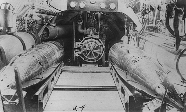 A 1912 view of the breech of the sole torpedo tube of USS Moccasin / A-4. Two torpedoes are on wooden skids in the foreground. The skids slid across t