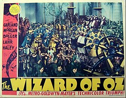 Lobby card with still of deleted musical number "Hail! Hail! The Witch Is Dead!", sung upon the return to the Emerald City Wizard of Oz lobby card.jpg