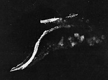 The disabled Ryūjō (top center) under attack from high altitude by B-17 bombers on 24 August 1942. The destroyer Amatsukaze (lower left) is moving away from Ryūjō at full speed and the destroyer Tokitsukaze (faintly visible, upper right) is backing away from the bow of Ryūjō in order to evade the B-17s' falling bombs.
