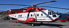 Sikorsky S-61N, jeden z prvních letounů ve flotile Air Greenland. Je z většiny bílý, jen v dolní a horní části se nachází červená. Jde o vrtulník.