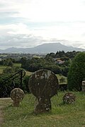 Fotografie a unui cimitir, cu stele discoide, pe un fundal de munți.