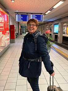 Teilnehmerin auf U-Bahnsteig mit Rucksack, in dem Rose steckt