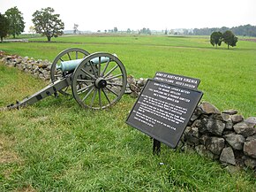 Fotografie ukazuje dělo vedle cedule s textem sboru armády Severní Virginie Longstreet, Hoodova divize, Henryho praporu.