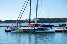 Barco azul y blanco amarrado a un pontón.  Detrás de él, al otro lado del pontón, un bote naranja: PRB.