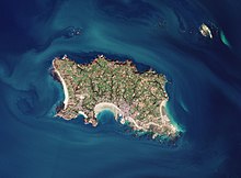 Zdjęcie satelitarne. Widać na nim wyspę Jersey z kosmosu. Na wyspie, na tym zdjęciu widoczne są pola, zabudowania oraz lasy, skaliste klify i plaże Jersey.