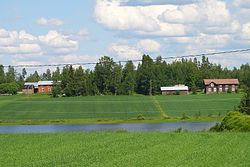 Koskutjärvi ja Ylivalliin johtavan tien varrella olevia maalaistaloja järven itäpuolella.