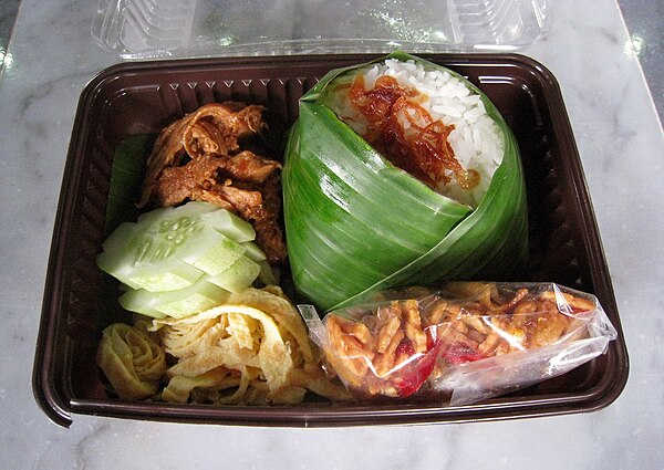 Packed nasi uduk with ayam suwir (shredded chicken), slices of cucumber, shredded omelette, and kering tempe (crispy deep-fried tempeh with sweet soy 