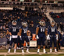 Nevada football players on the sideline before a game at Mackay Stadium in 2021 Nevada C-130 Pilots honored during Coin Toss prior to Nevada versus Air Force football game (cropped).jpg
