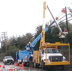 Lineworkers repairing electricity distribution lines that supply power to homes PGE linemen at work.jpg
