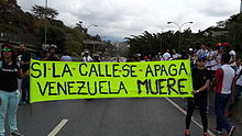 Opposition protesters holding a sign saying "If the street turns off, Venezuela dies". Protesters with sign Venezuela 2014.jpg