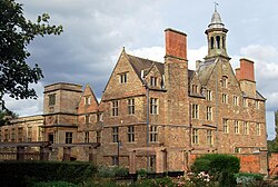 View of part of Rufford Abbey to left of image with the House to right both finished in local sandstone against a dappled sky