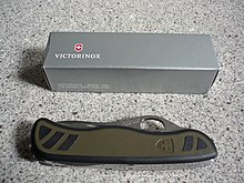 A Swiss army knife -- the soldier knife (Soldatenmesser) issued by the Swiss Armed Forces (2008 model). The cardboard box shows the Swiss coat of arms used in the company logo by the manufacturer, Victorinox, while relief depicted on one grip on the knife itself is the coat of arms used by the federal authorities. Soldatenmesser 08-1.JPG