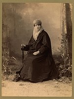 Turecká žena, plný portrét, sedící, hledící dopředu, držící slunečník