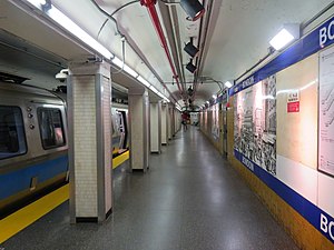 A subway train at an underground platform with blue signage