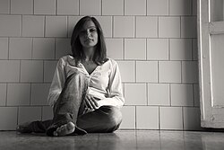 File:Woman against tiled wall barefoot.jpg