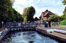 Caversham Lock on the River Thames, with its chamber nearly filled. Visible on top of the gates are the hydraulic mechanisms that raise and lower the sluices in their raised position. To the right is one of two pedestals which are used to operate the sluices, as well as open and close the gates.
