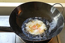 Egg being fried in a karahi Fried eggs (25056120628).jpg