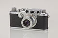 En Kompaktkamera fan Leica (1950ern). Döör dit Skukhol sjocht em en bet üđers üs di Kamera dit āpnemt.