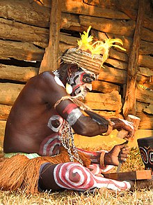 Seorang dari suku Asmat tengah membuat ukiran kayu. Foto : Wikipedia