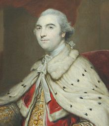 Half-length portrait of a man wearing furred robes and a white wig and looking regal. Underneath his white robes, he is wearing red and gold and he is sitting in a red chair.