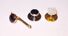 From left to right: A sliding-pin stud set with red glass; a screw-back evening stud set with cabochon onyx; and a screw-back stud with mother-of-pearl affixed to brass. ShirtStuds.jpg