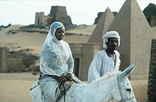 Sudanese woman wearing contemporary clothes, and Sudanese man wearing a jalabiya Sudan Meroe Pyramids 15jan2005.jpg