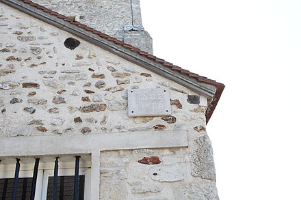 Plaque avec un texte en alphabet grec placé sur le côté de l’église de Lommoye