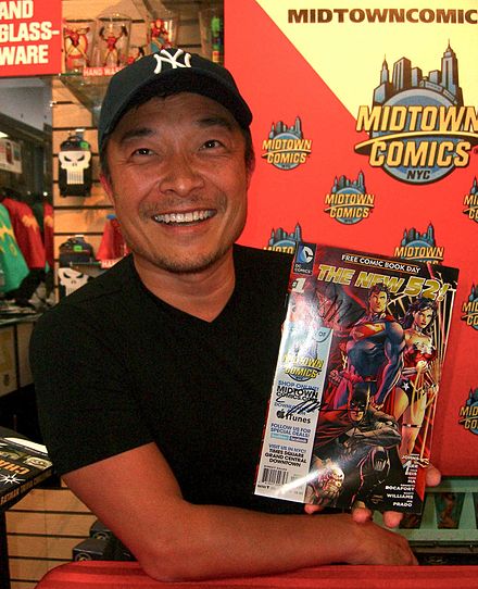 DC Comics artist Jim Lee holding a copy of The New 52 2012 Free Comic Book Day issue.
