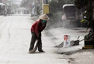 Muž zametá sopečný popel po erupci indonéské sopky Kelut