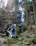 Artificial waterfall with a brick drain and bridge