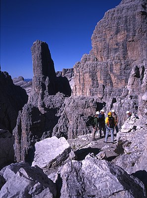 Horolezecká skupina na Sentiero delle Bocchette Centrali, v pozadí Guglia (Campanile Basso)