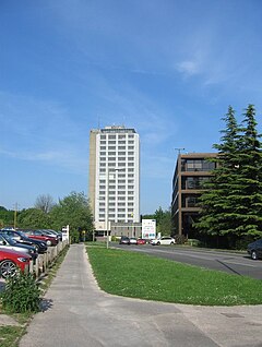 Skyscraper in distance against a blue sky with roads and grass in front