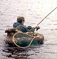 An angler in a float tube plays a pike.
