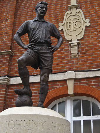 Johnny Haynes (1934–2005), Fulham's most famous player, in his classic 'hand-on-hip' pose, outside the stand named after him