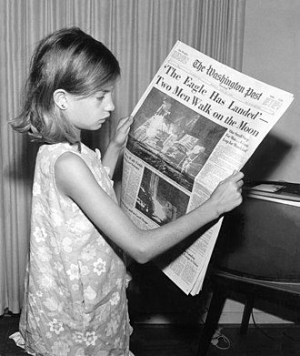 A girl holds a copy of The Washington Post reporting the Apollo 11 Moon landing on July 21, 1969 Land on the Moon 7 21 1969-repair.jpg