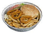 A bacon cheeseburger from a New York City diner in a to-go container, with a pickle slice, onion rings, coleslaw and french fries NYC-Diner-ToGo-Cheeseburger-Deluxe.jpg