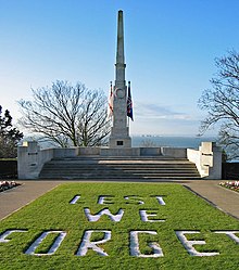 A stone obelisk behind a lawn; the words "lest we forget" are marked on the lawn in stone chippings