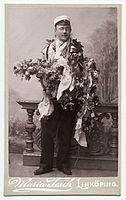 Studentský portrét Olle Faleije ve studentském klobouku a ověšeném květinami, Nordiska Museet