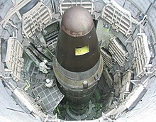 View looking down a textured metal cylindrical enclosure. Inside sits a long, thin missile that is cylindrical in shape with a conical nose.