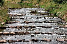 Una sucesión de hileras de bloques de piedra a través de un arroyo.