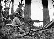 Soldiers operating a heavy machine gun amidst a jungle scene