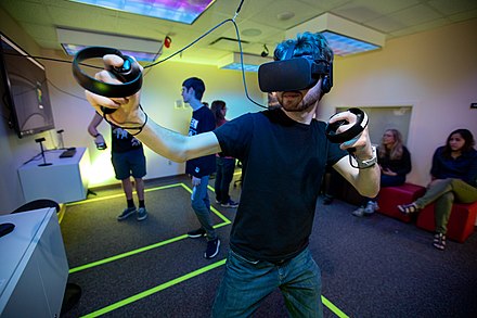 A player using the Oculus Rift virtual reality headset and associated controllers to control a game