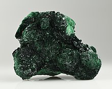 Unregelmäßiger grüner Stein mit kristallinen Nadeln in zweierlei grüntönen – einem dunklen Moosgrün und einem helleren Grün, das an Algen erinnert